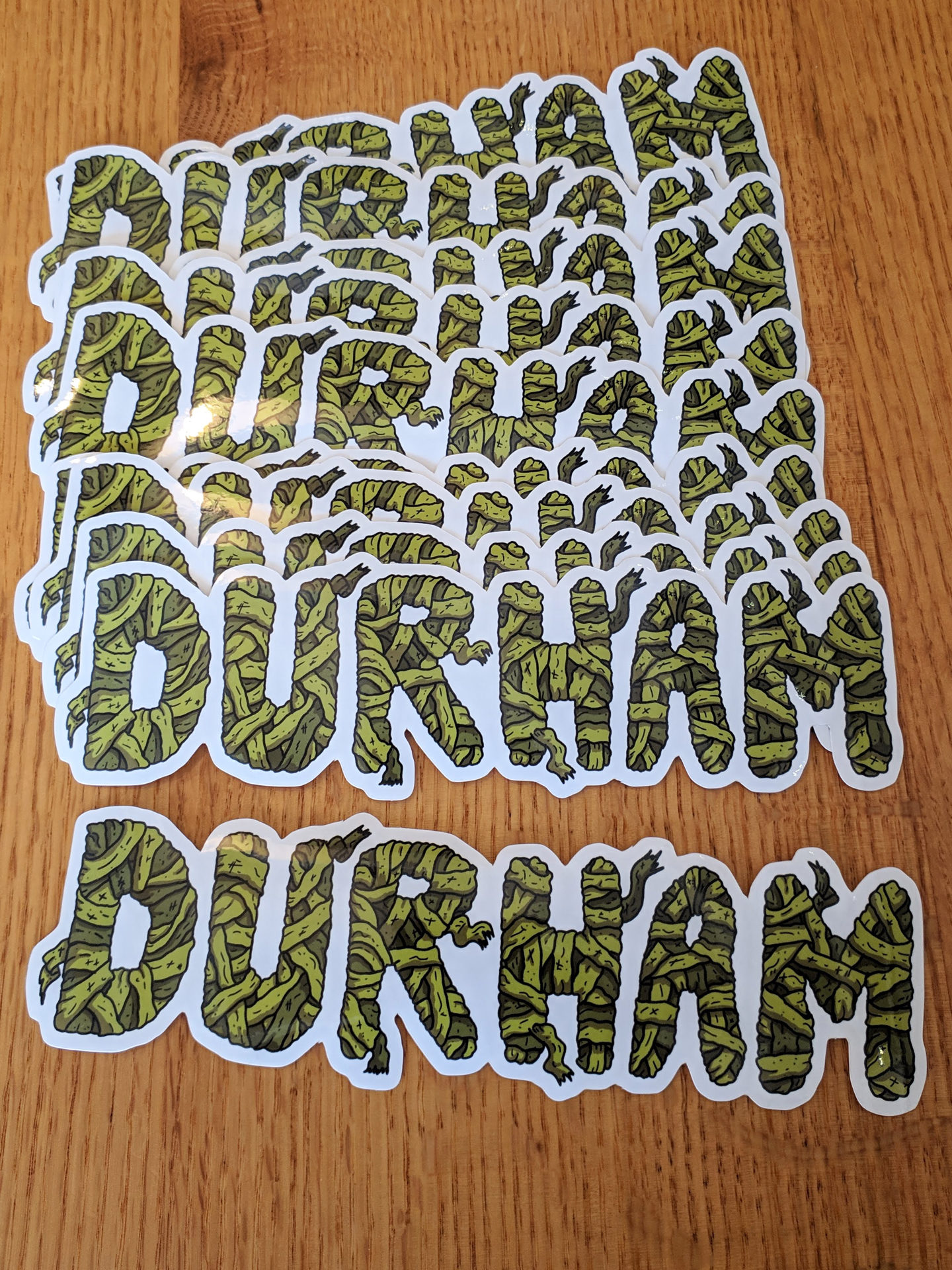 stack of glossy mummy-themed DURHAM city text bumper stickrs